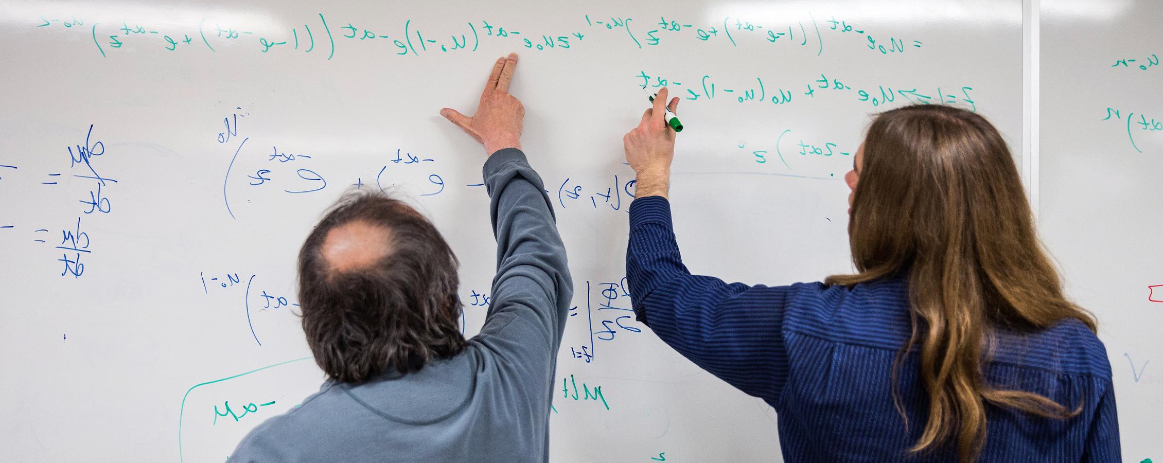 Mathematics student and instructor work on whiteboard