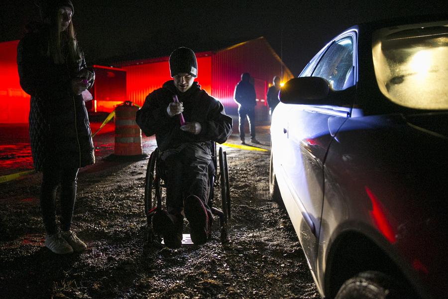 A student is outside in the dark next to a car during a crime scene simulation.