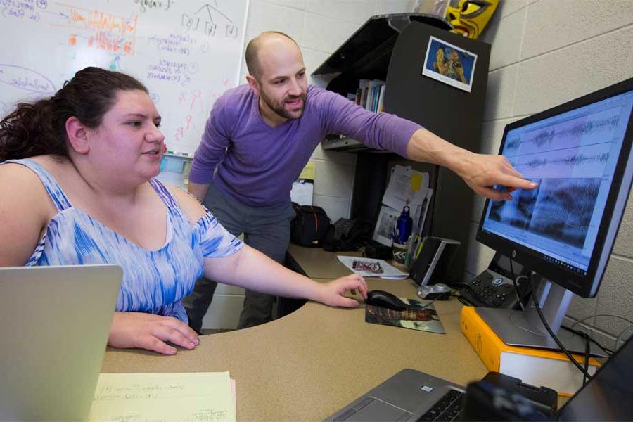 Nate Maddux works with a student at a computer.